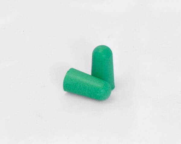 a pair of 503 PPE Foam Formable Earplugs sits on a white background. one is standing upright like a tower, the other lays flat on a white table