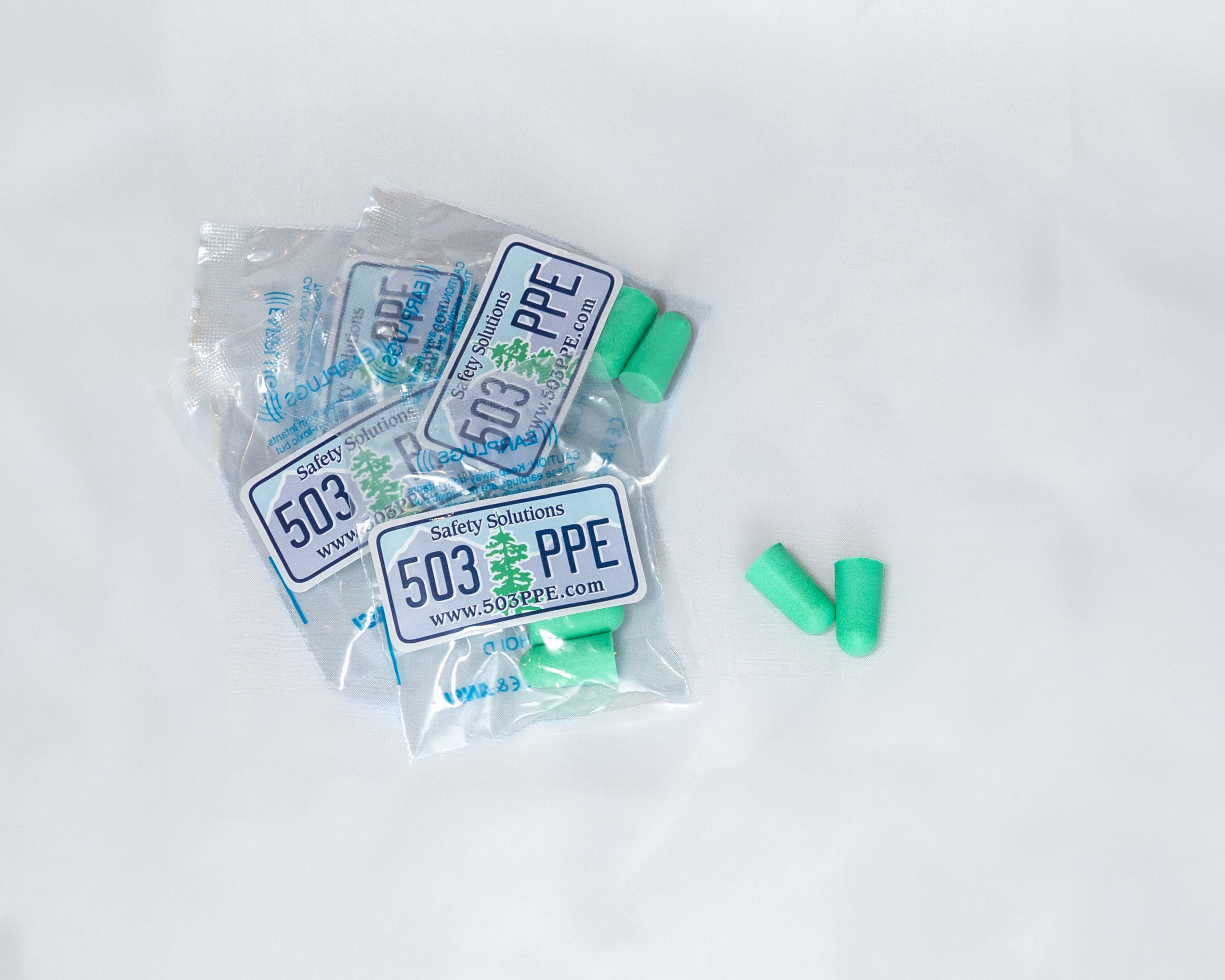 a small pile of 503 PPE Foam Formable Earplugs in their individually wrapped plastic packaging with logo sits on a white background.